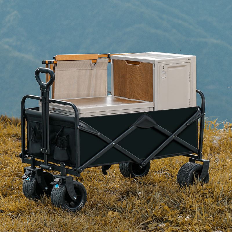 Black folding camping wagon cart with tank wheels and telescopic handle on white background